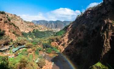 Beautiful canyon landscape with river and rainbow under clear blue sky, perfect for summer travel imagery.